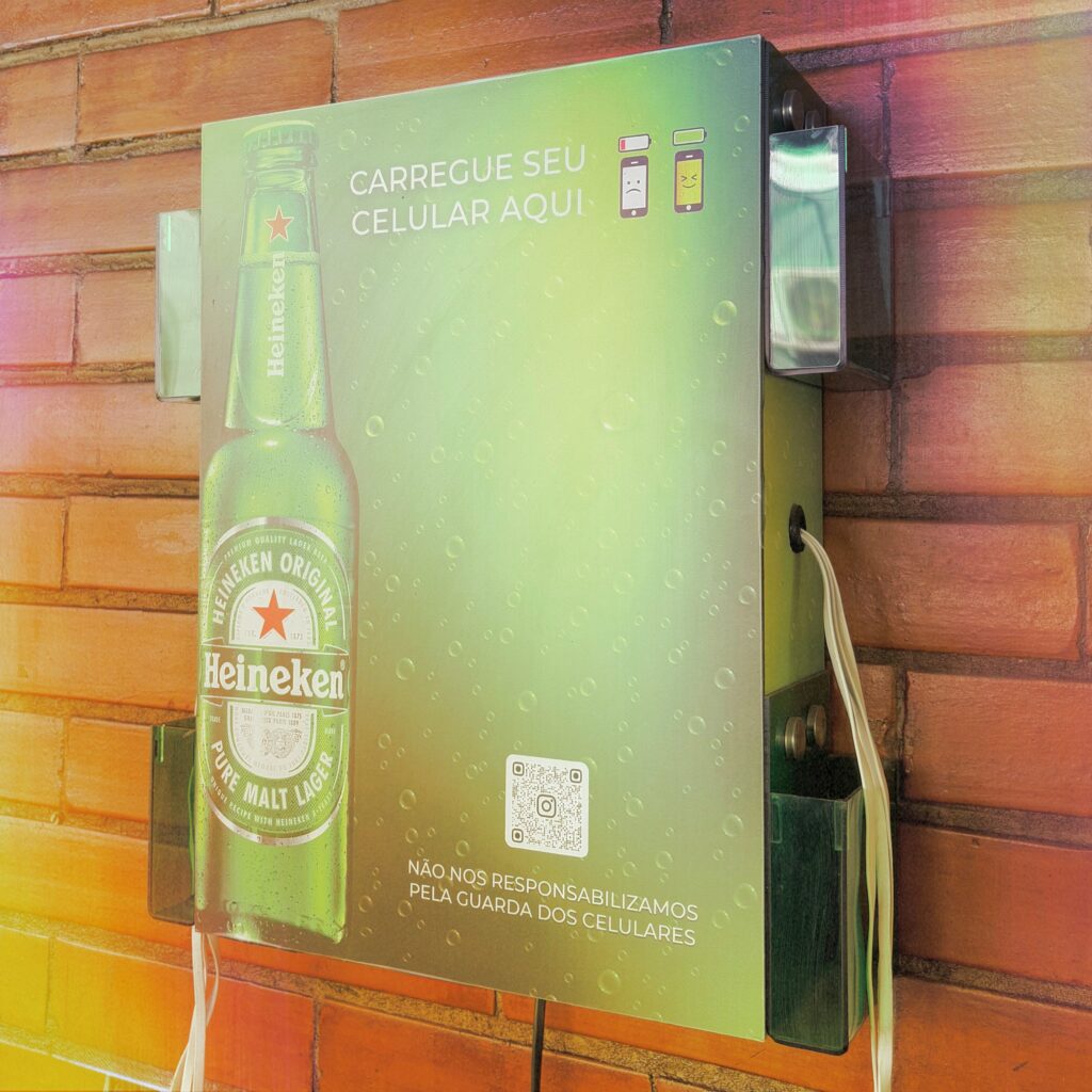 Totem de Parede carregador de celular personalizado com a marca Heineken instalado em parede de tijolos